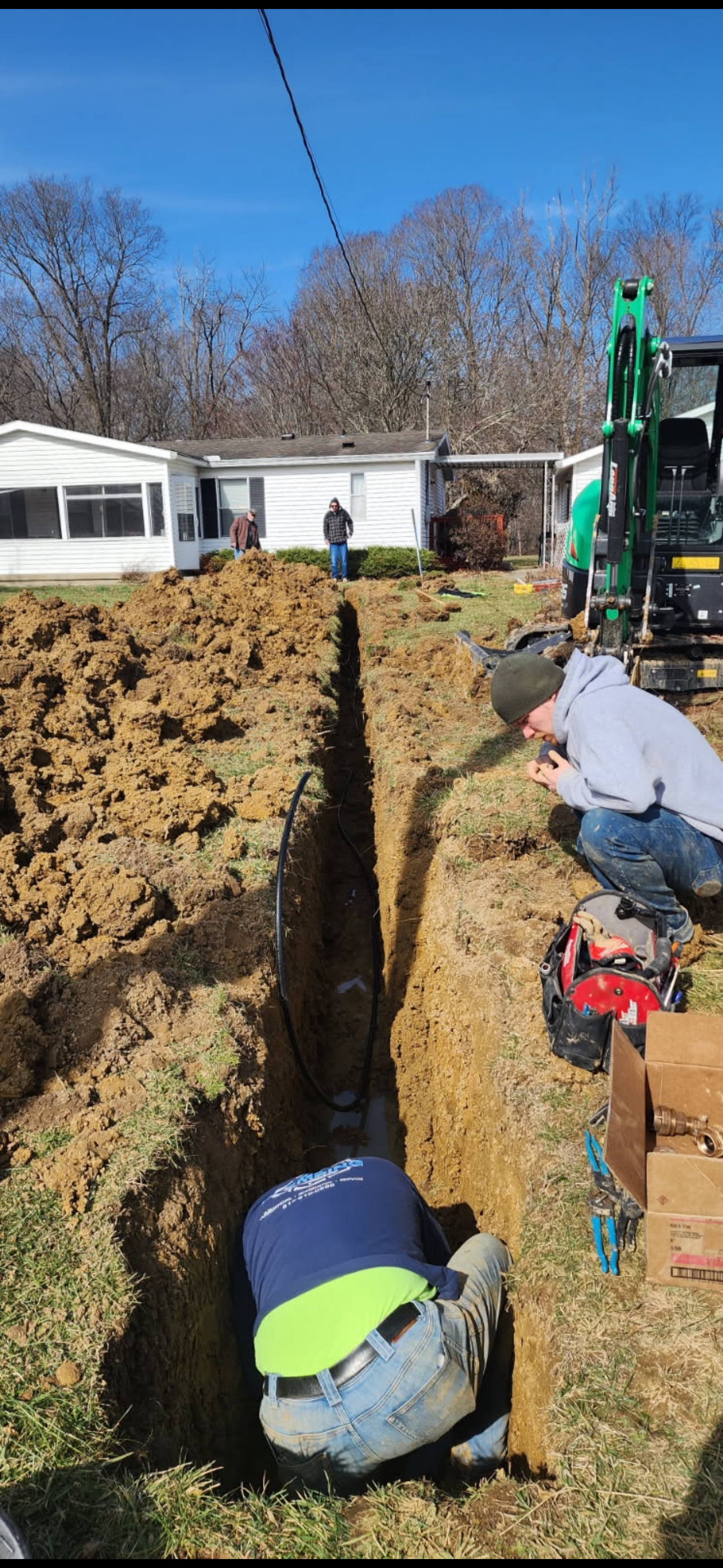 DE Plumbing crew working in a trench during sewer line replacement